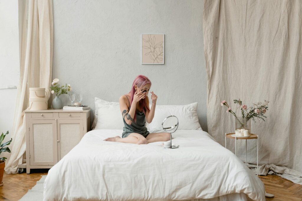 Young woman enjoying a skincare routine in a minimalist bedroom, surrounded by nature-inspired decor.